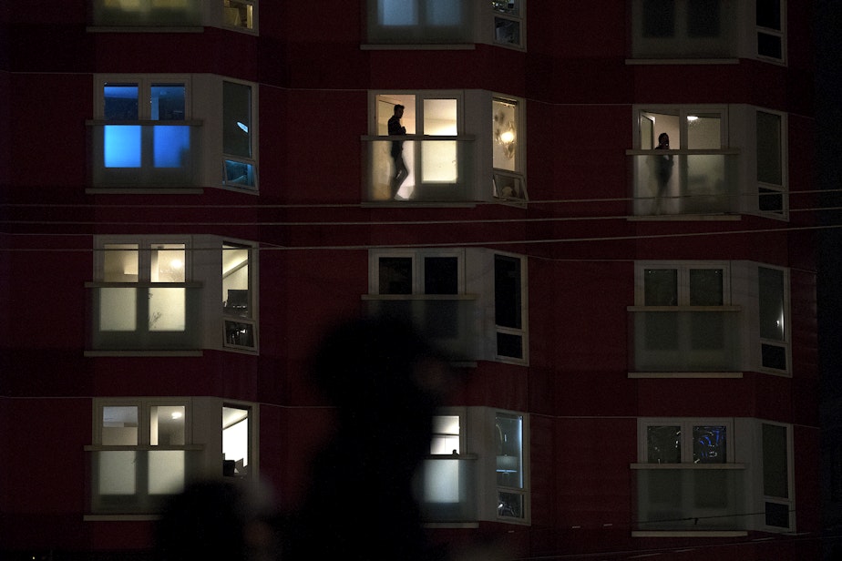 caption: People watch from their apartment windows as various protest groups join together before marching on the night of the 2020 Presidential election on Tuesday, November 3, 2020, at Cascade Playground in Seattle.